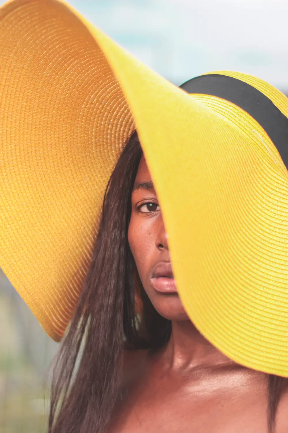 Close-up of girl adorning a yellow sun hat staring into the camera