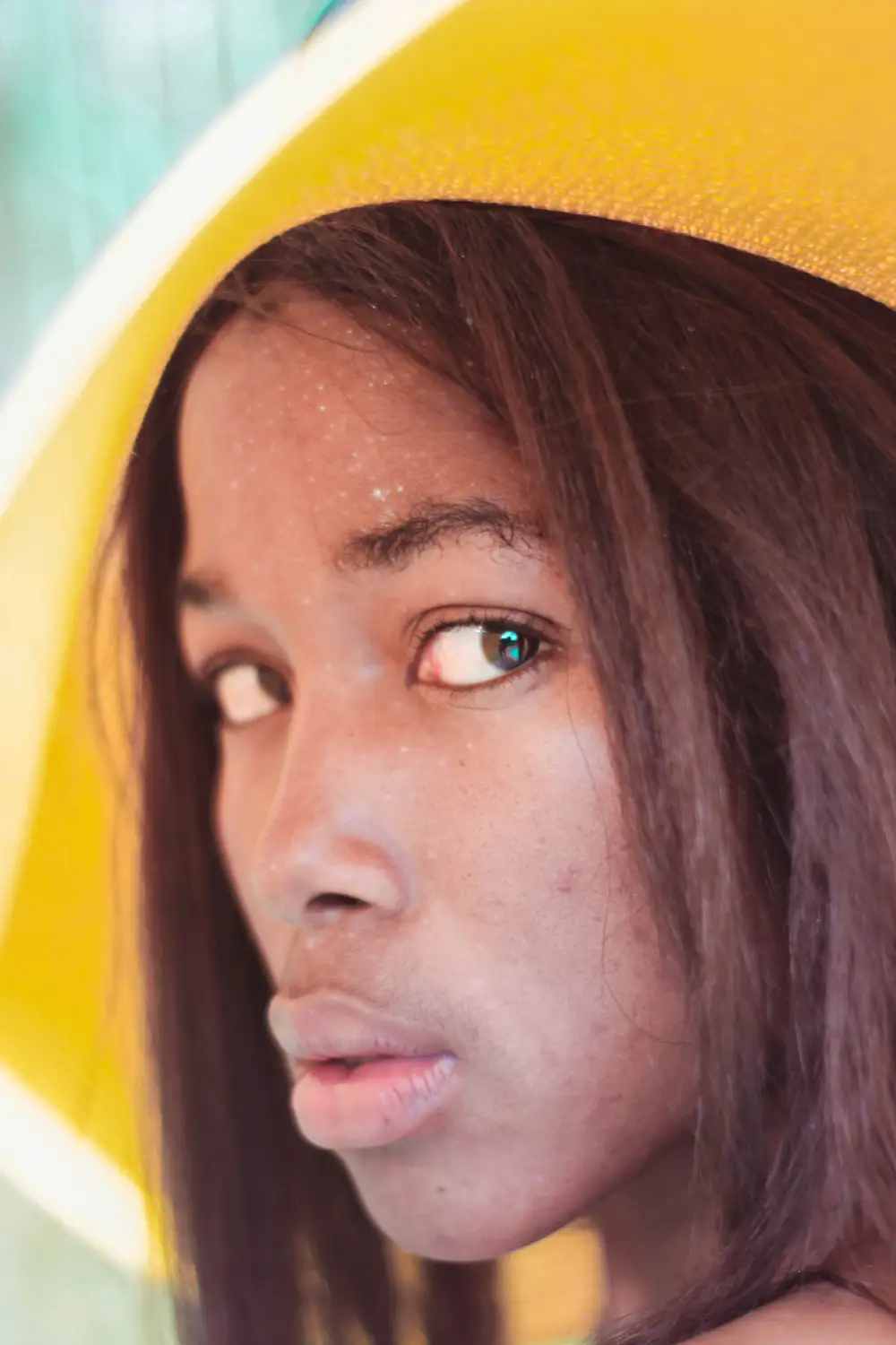 Close-up of girl adorning a yellow sun hat staring into the camera
