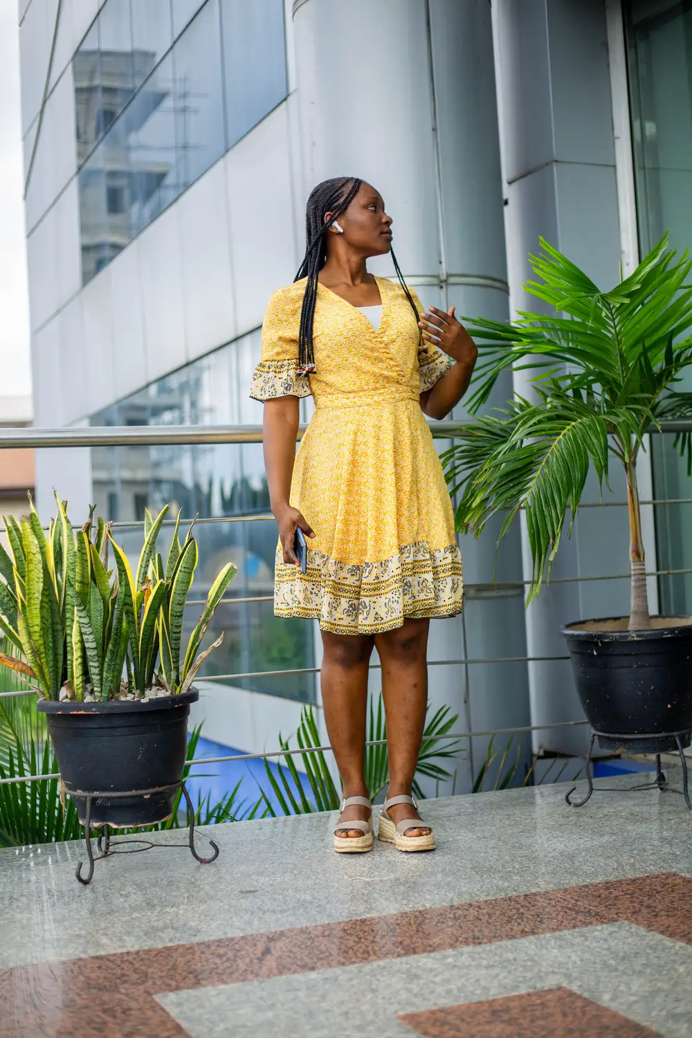 a woman on a yellow dress stands and looks away