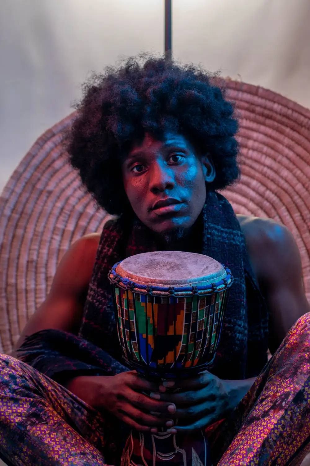 model on afro holds his talking drum for a photoshoot
