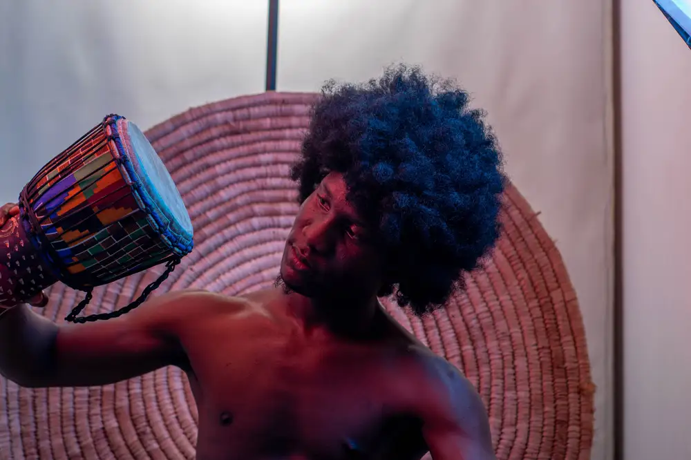 model in afro hairstyle holds his drum and looks at it