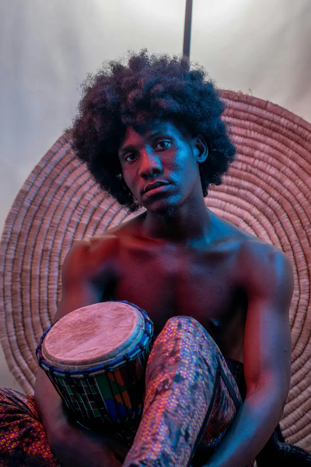 model on afro hairstyle holds his drum with his laps