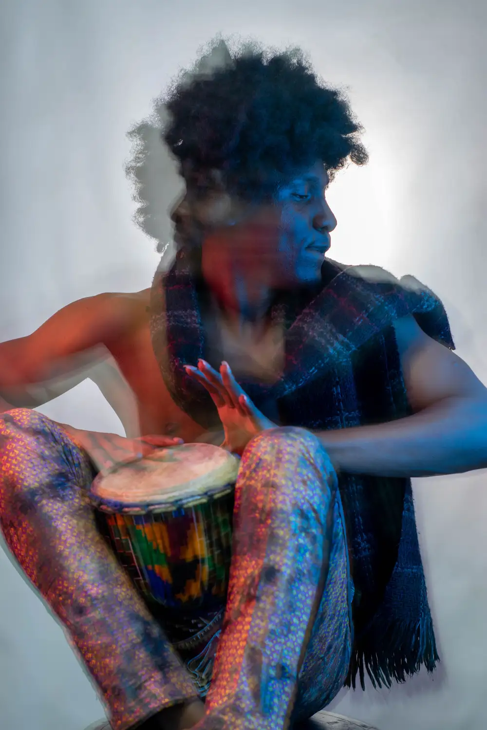 model on afro hairstyle plays his drum and looks away
