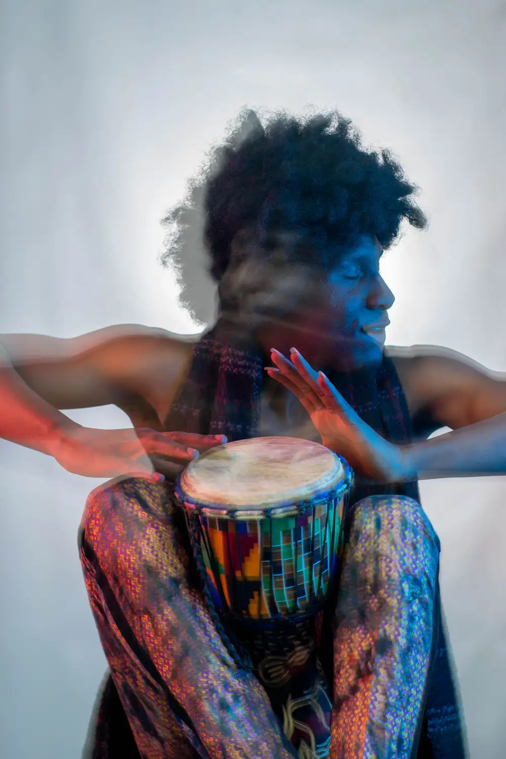 model on afro hairstyle plays his drum while looking away