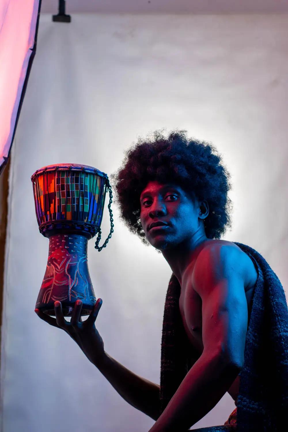 model on afro hairstyle holds his drum with one hand