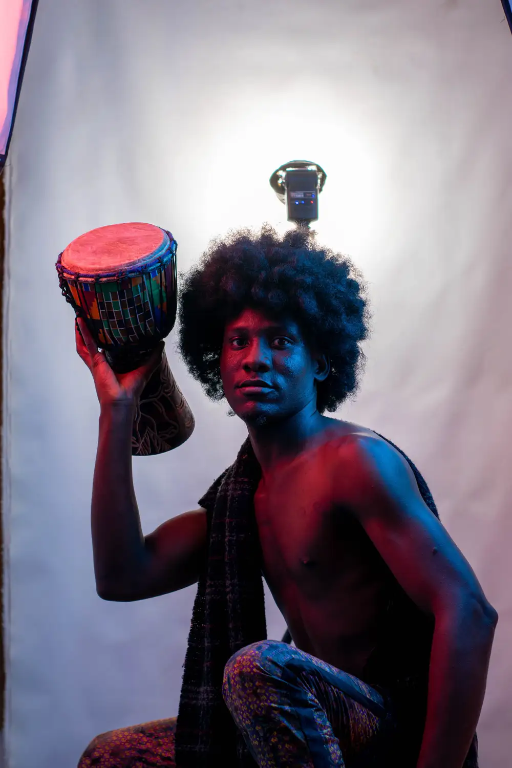 model on afro hairstyle raises his drum with one hand
