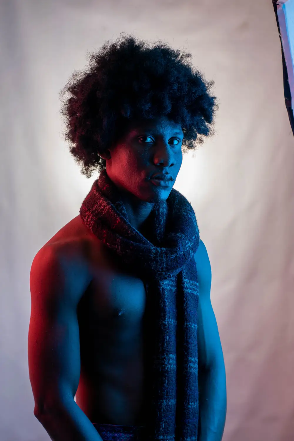 model on afro hair style puts a scarf around his neck