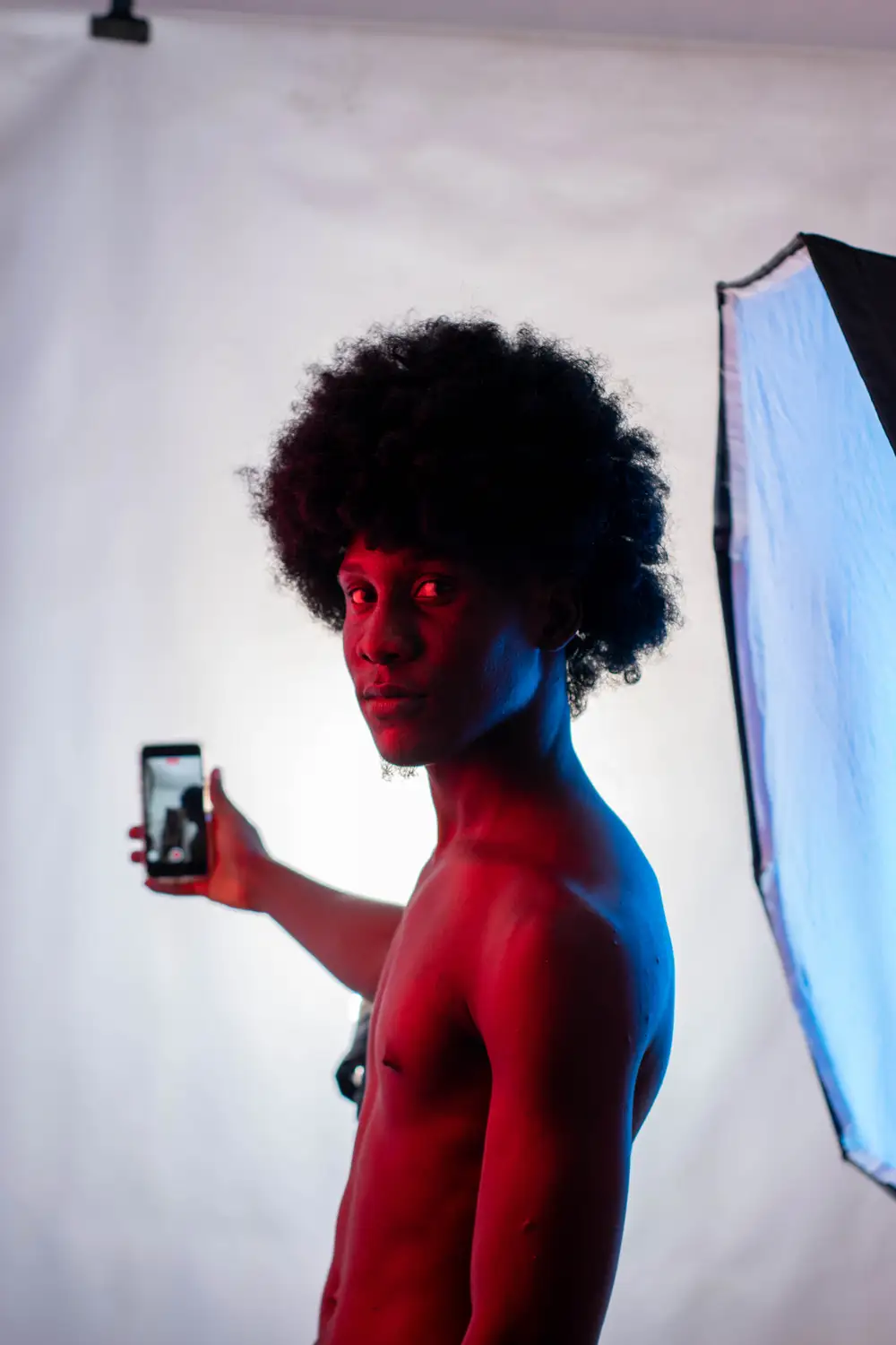 model in afro hairstyle holds his phone for a selfie