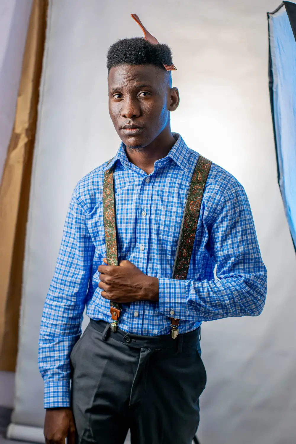 man in blue coloured shirt holds his belt