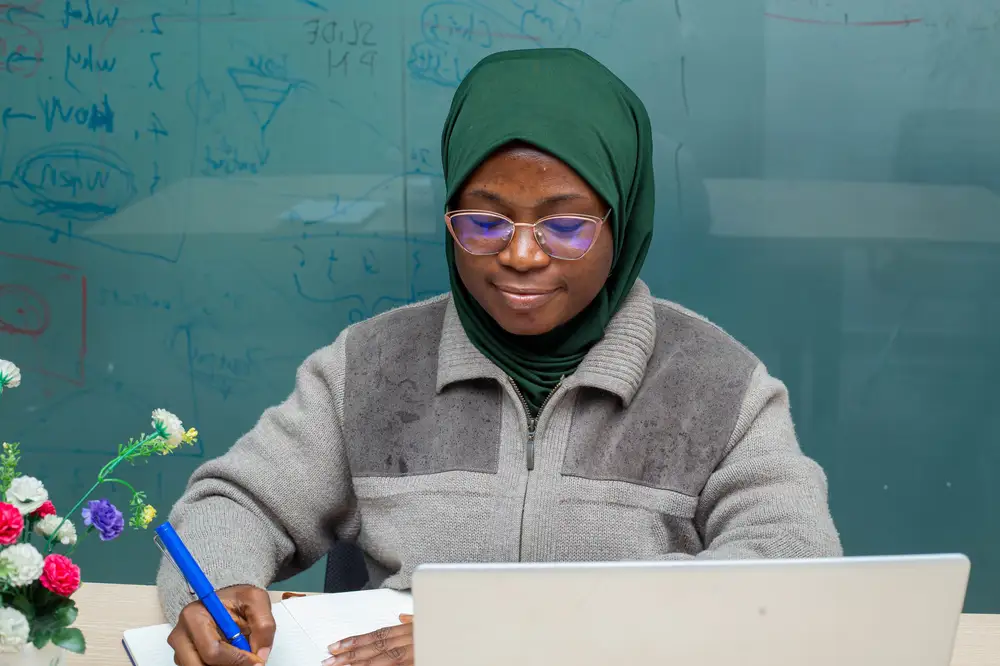 Muslim lady on green hair cover and glasses write a note