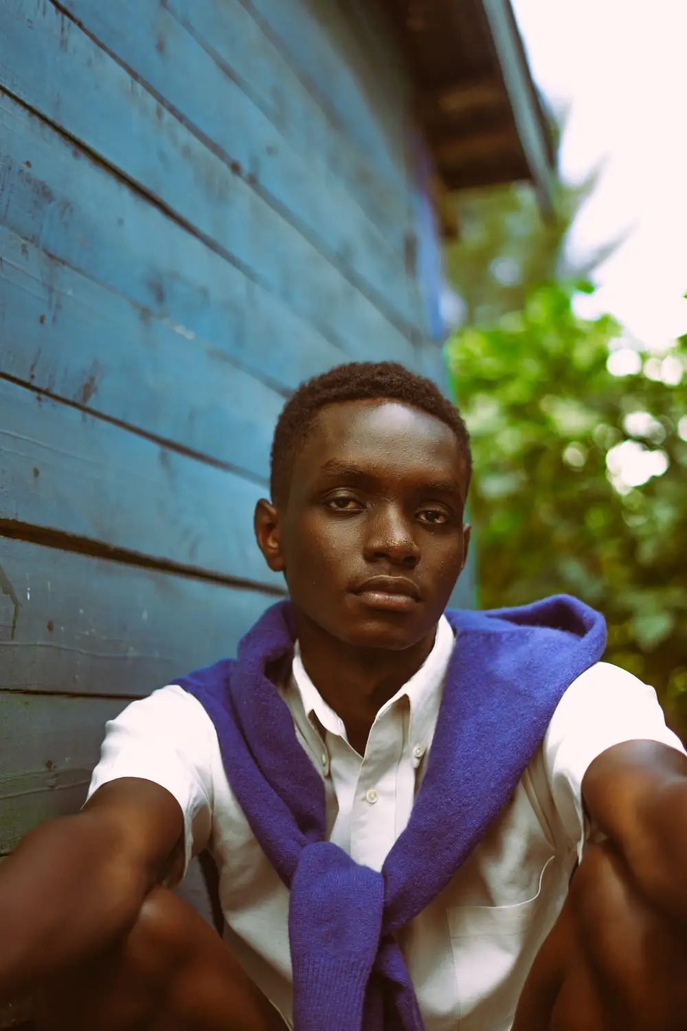 Guy sitting next to a blue wall