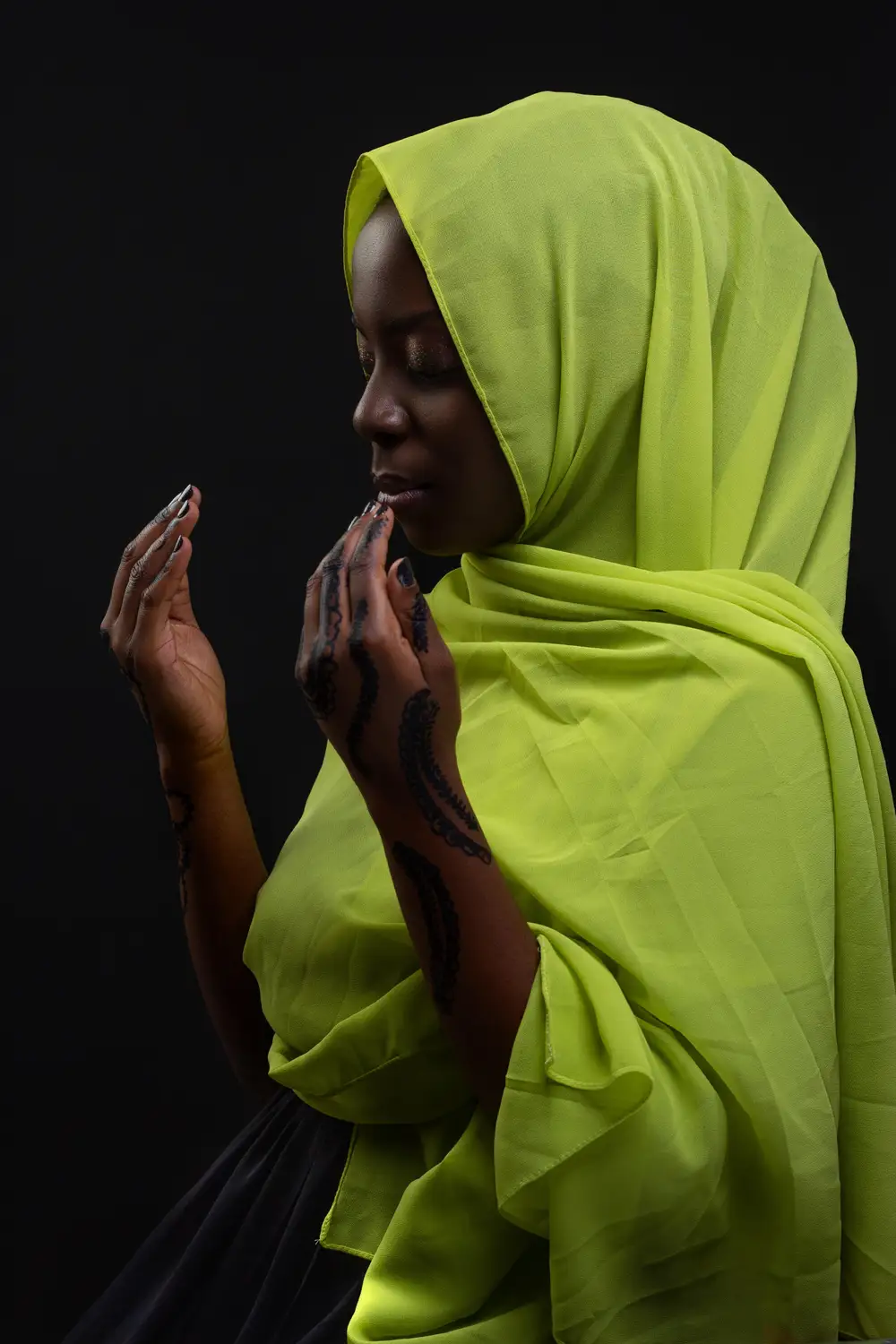 A muslim woman in green coloured hijab praying