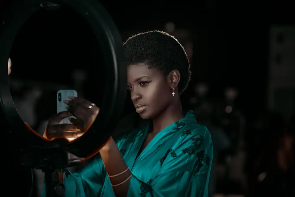 A lady on afro placing her iPhone on a ring light
