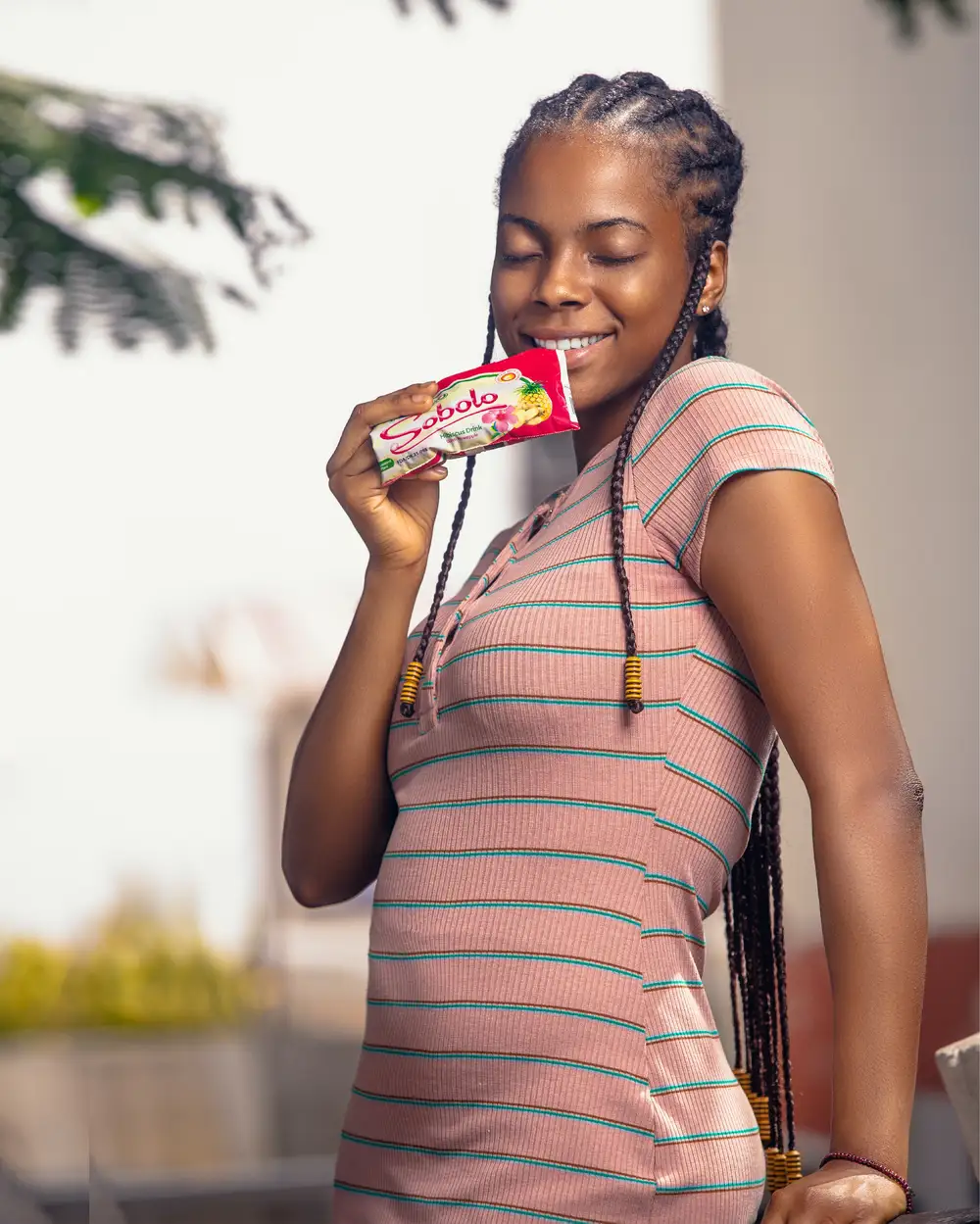 A beautiful lady drinking sobolo sachet drink