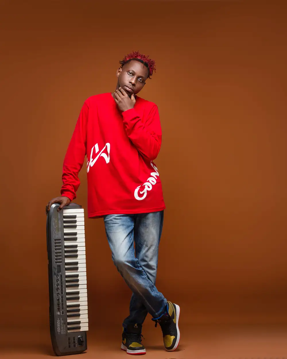 Black boy on red top and blue jeans posing with a keyboard