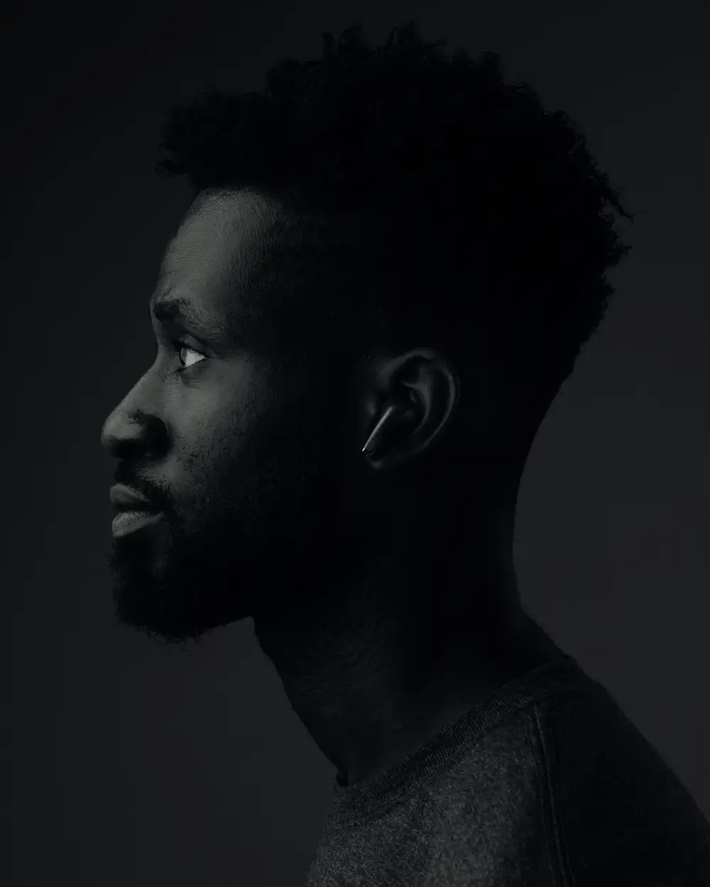 Black and white head portrait of a black man putting on earphones