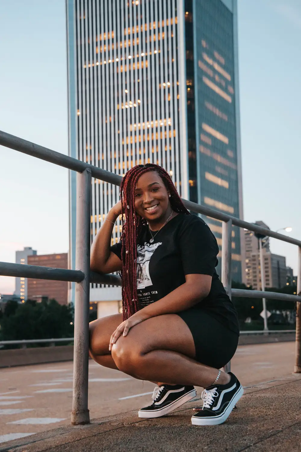 Beautiful lady wearing black and squatting in front of a tall building