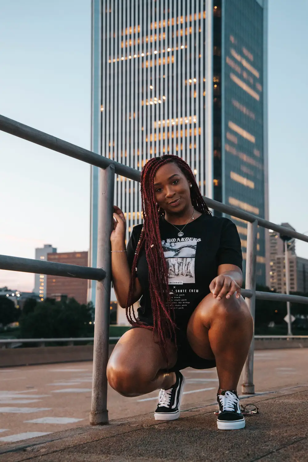 Young lady squatting in front of a tall building