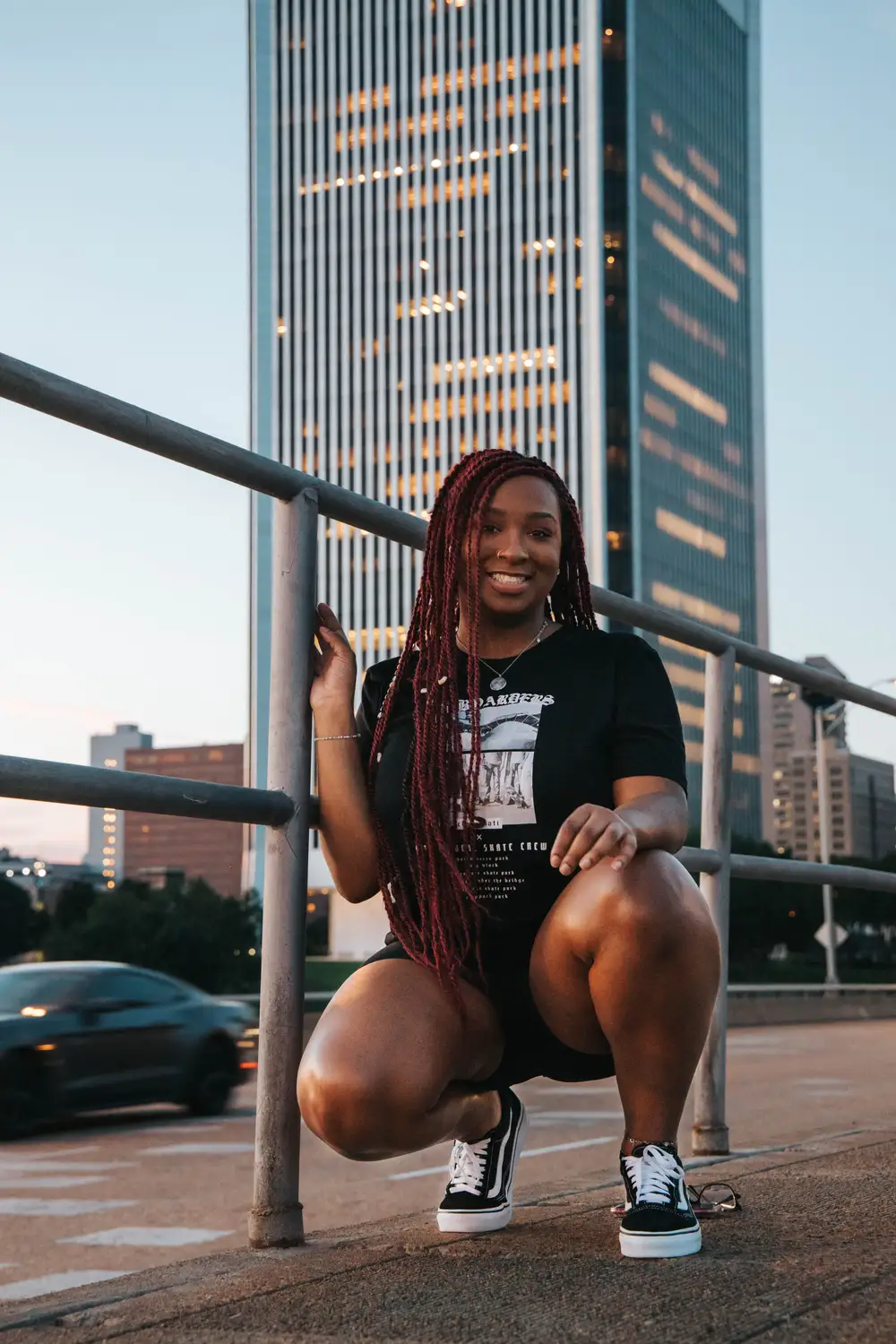 Smiling young woman squatting in front of a building