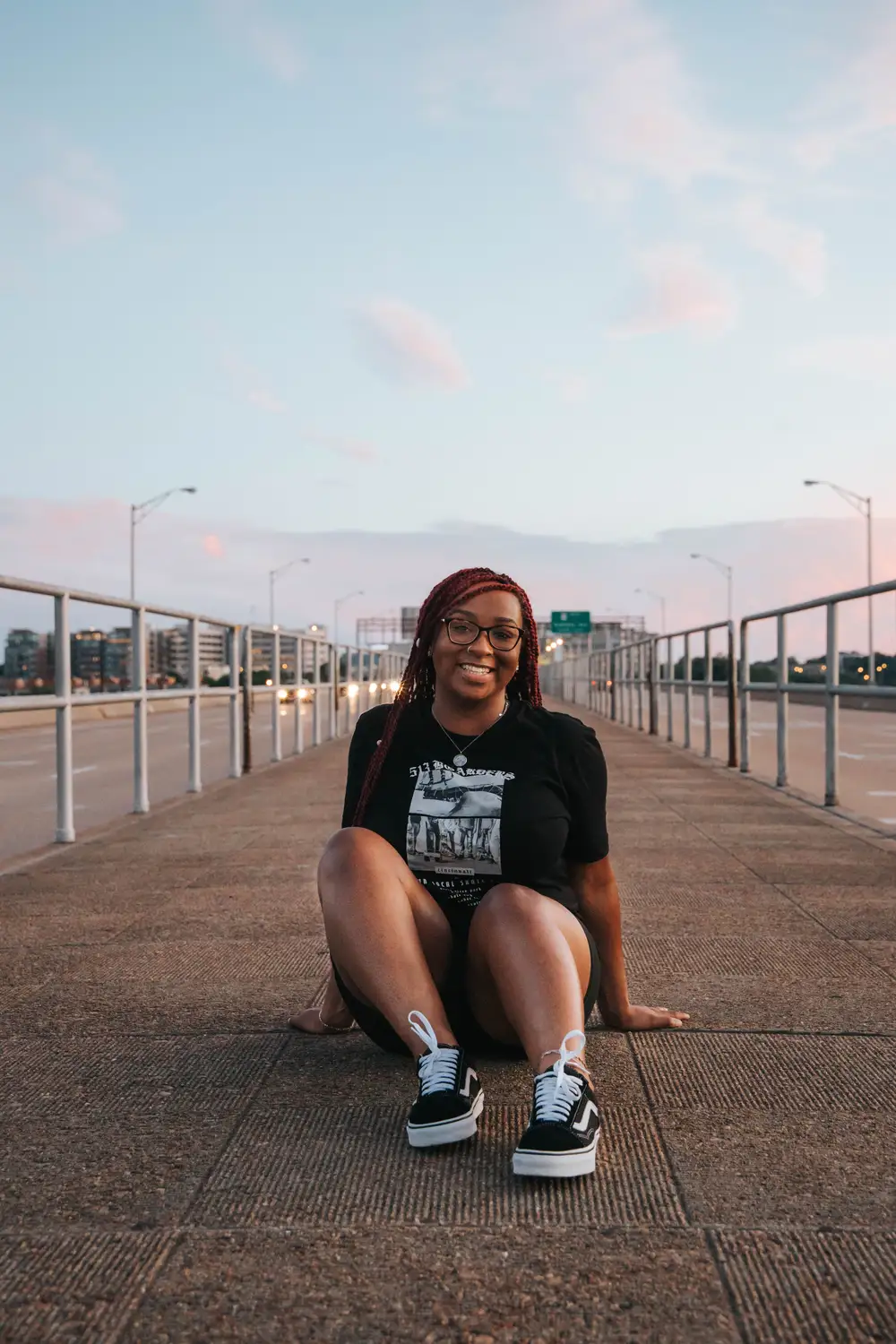 Smiling young lady sitting between two roads