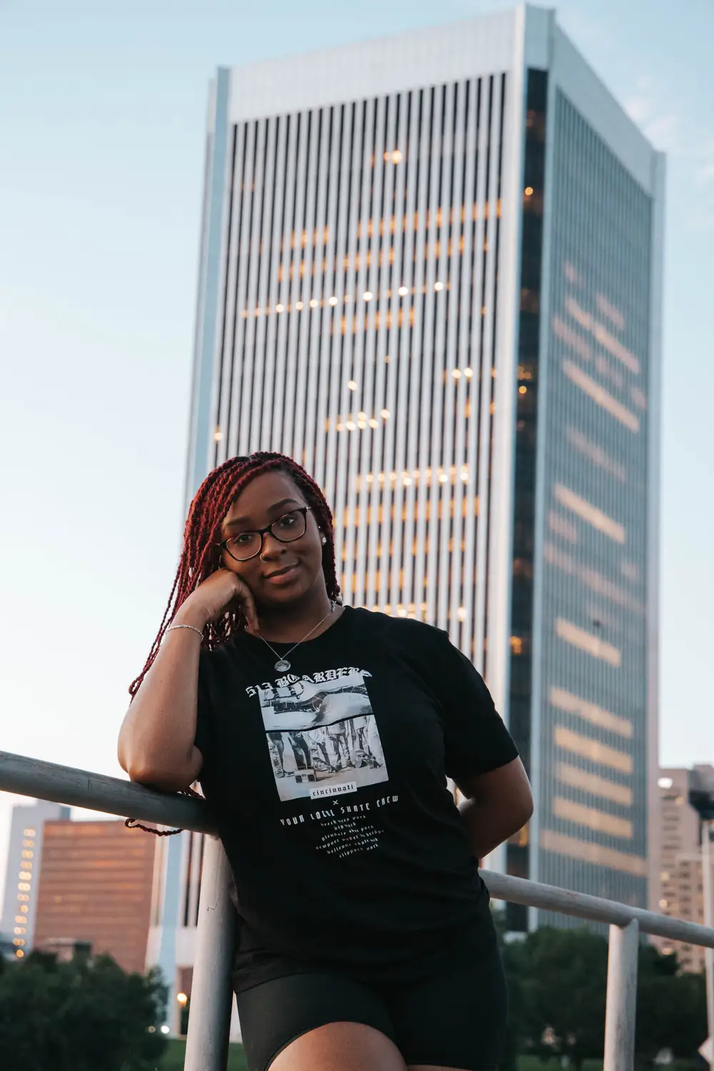 Lady leaning on a railing in front of a tall building