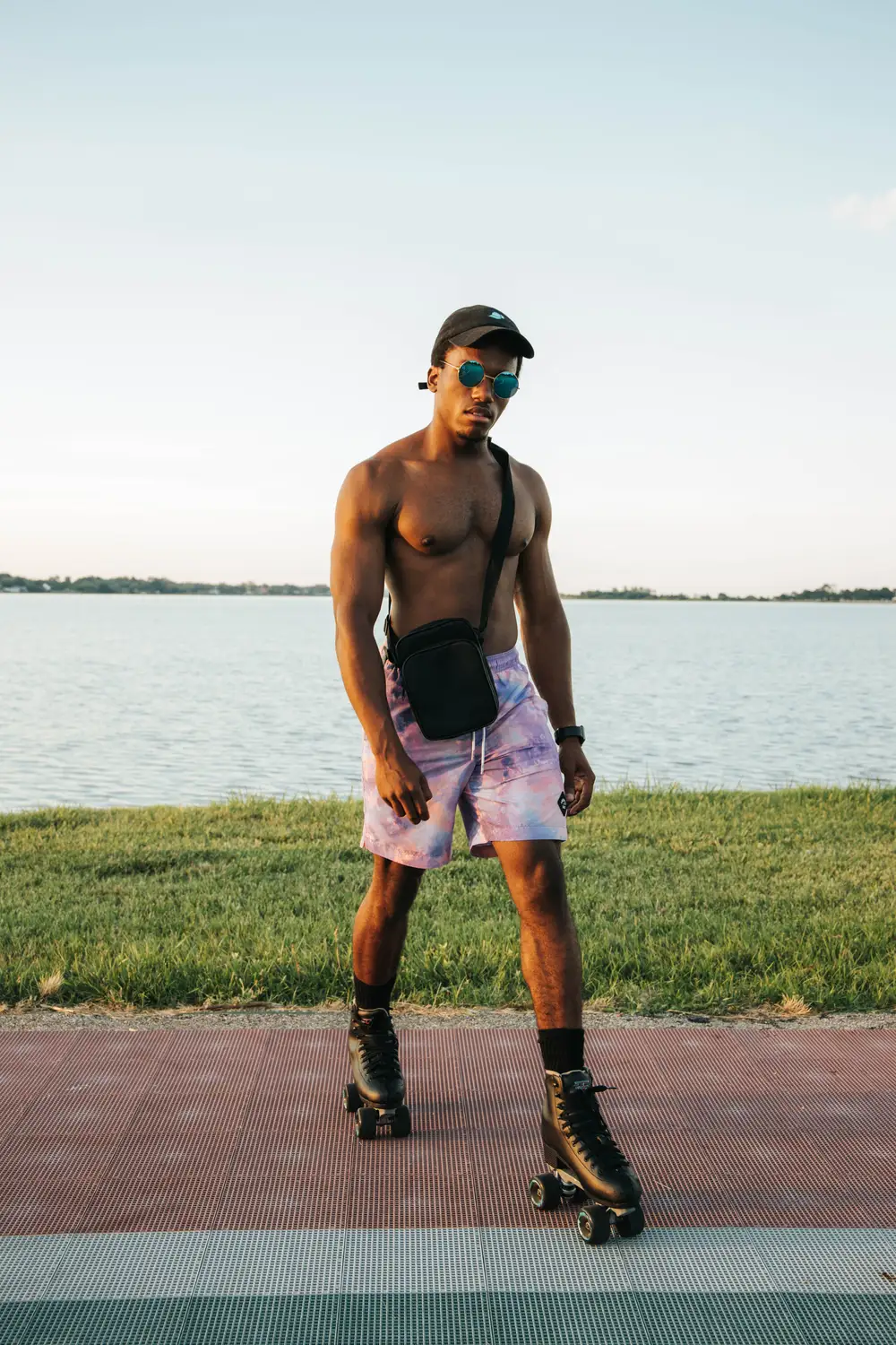 A shirtless skater wearing a short and a face cap by the river