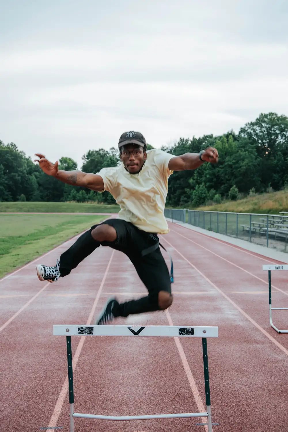 Young black man jumping a hurdle in a track