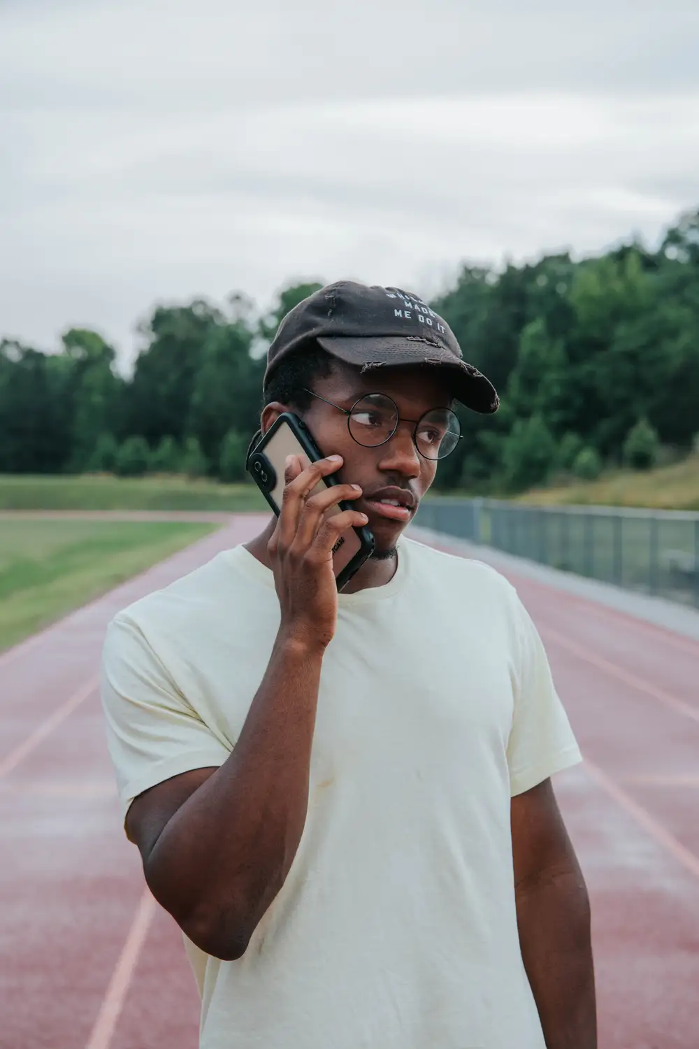 Young black man taking a call on a track