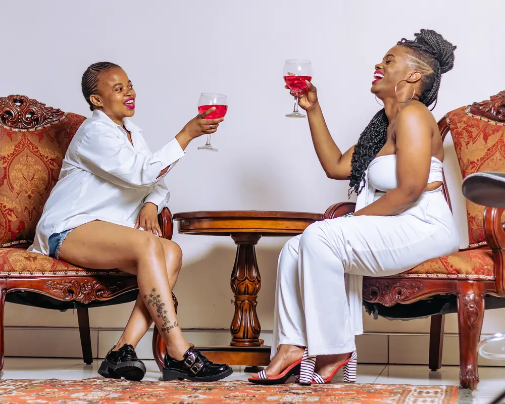 mother in white shares a glass of wine with her friend