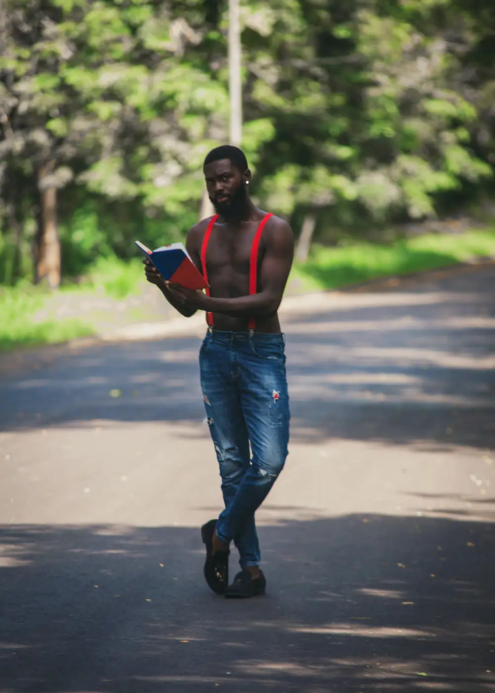 Man posing on the road with a book