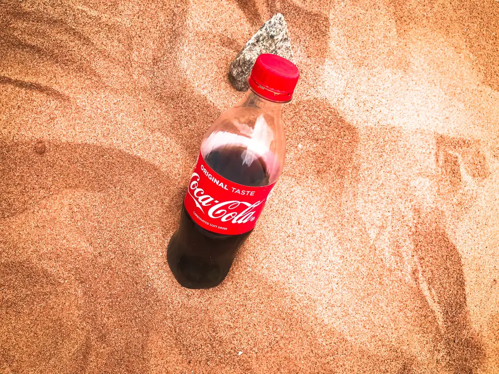 Bottle of coke in sand