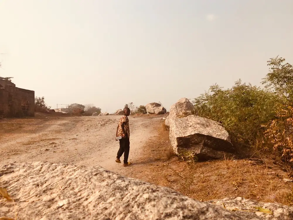 Boy standing beside a rock