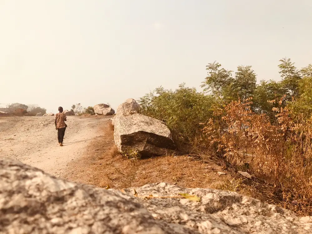 Boy walking in beside a rock