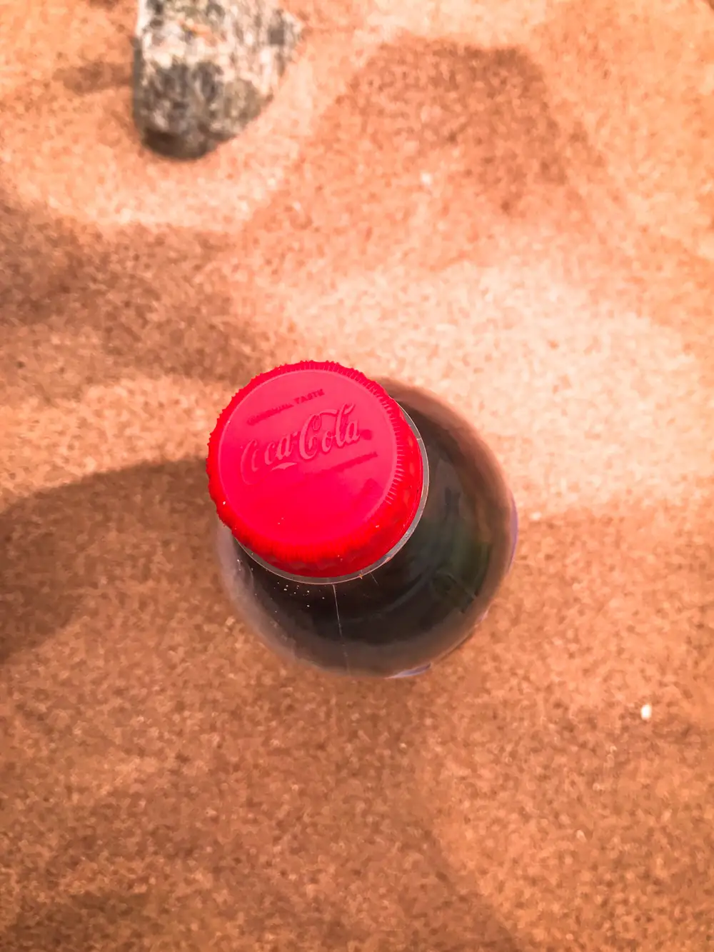 Up close bottle of coke in sand