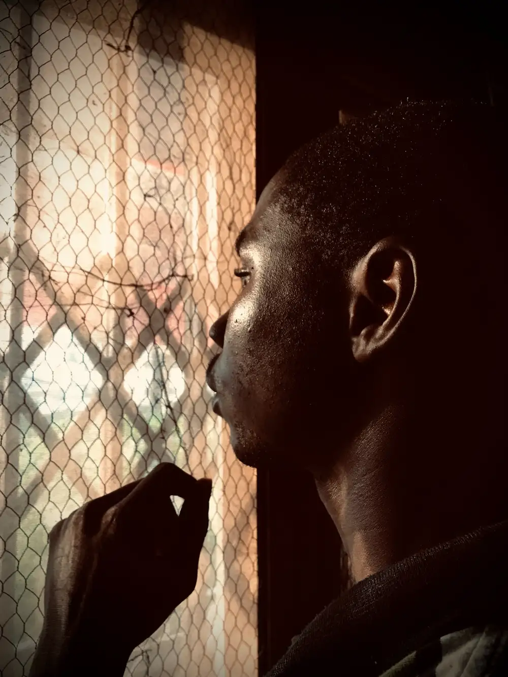 up close view of a guy looking outside through a net door