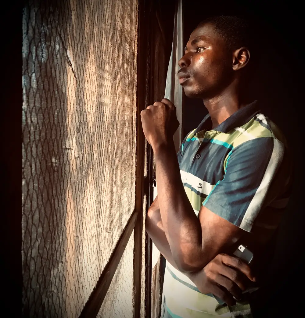 Guy looking outside through a net door