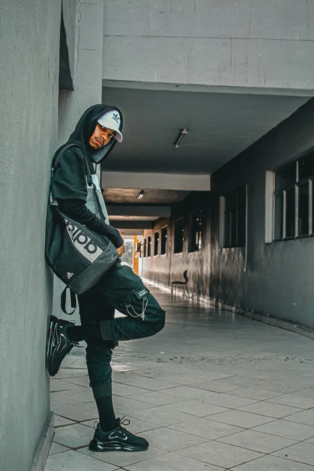 Boy dressed in a hoodie with a white cap and adidas bag