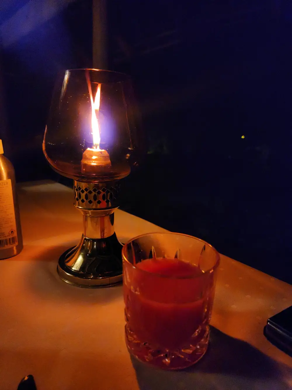 A drink and a lit candle on a table