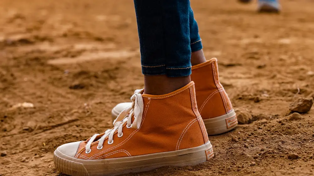 Feet of a person wearing sneakers standing in brown soil