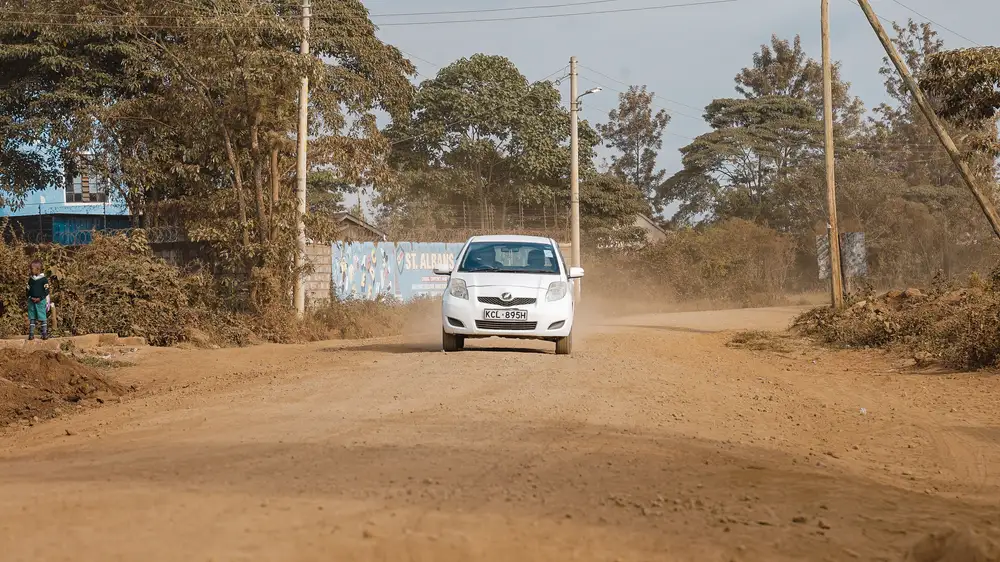 Car driving along a brown dusty road