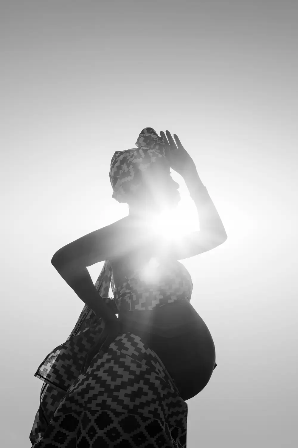 Pregnant Woman standing before a ray of sun