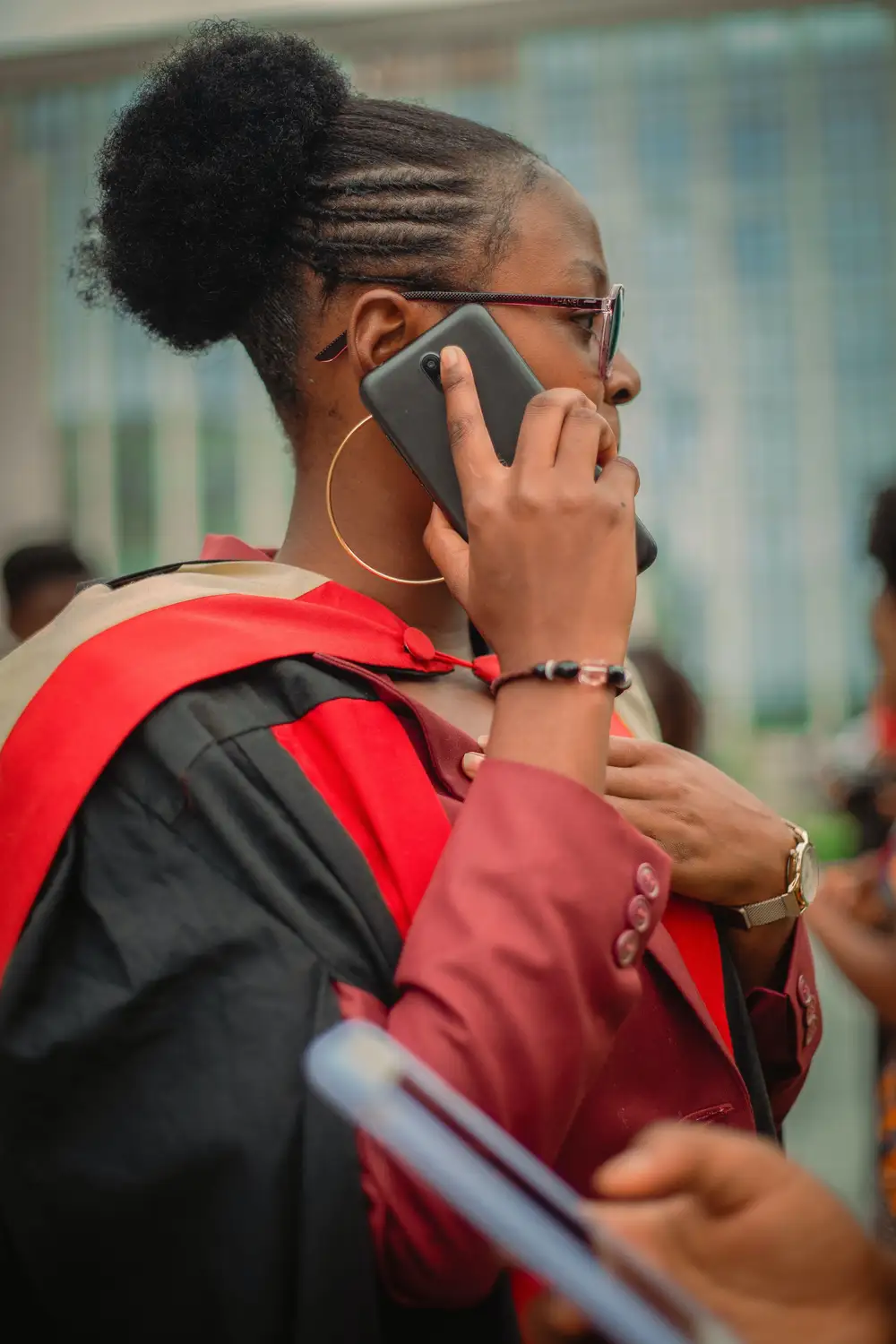 woman in a graduation gown making a phone call