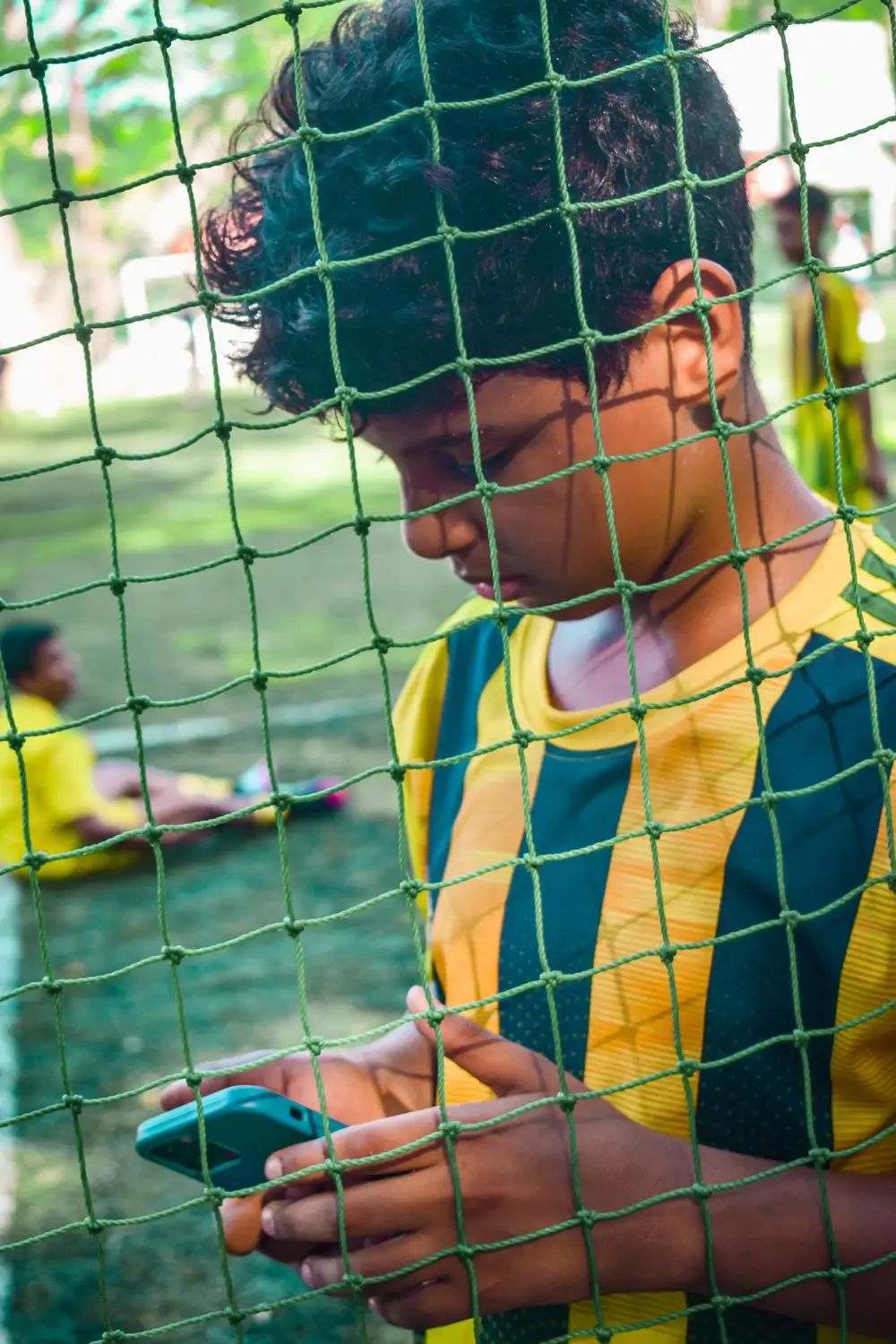 Boy holding a phone on a football field