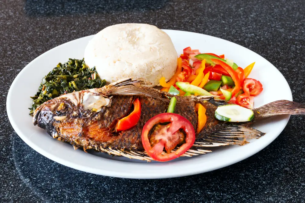 A plate of banku and tilapia fish with vegetables