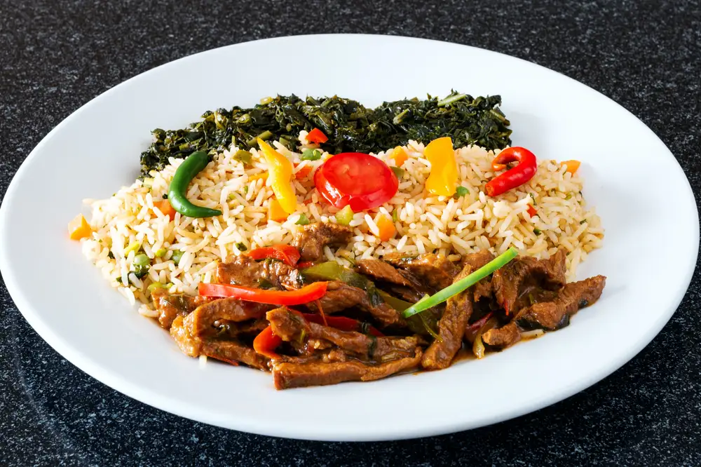 Rice and sauced meat with vegetables on a plate
