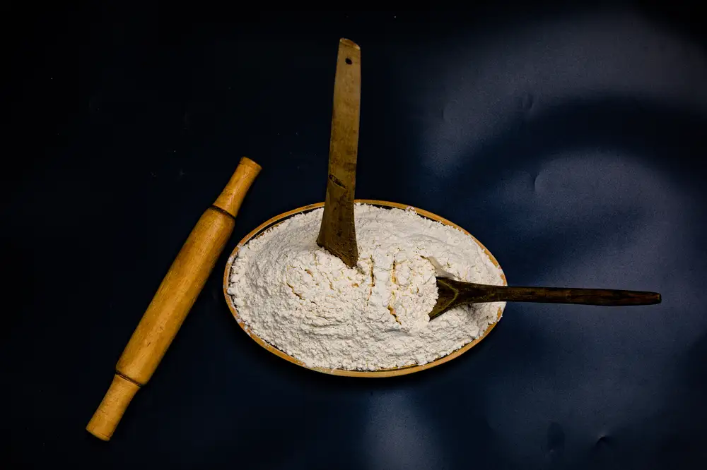Rolling pin beside wooding sticks in a plate of baking flour