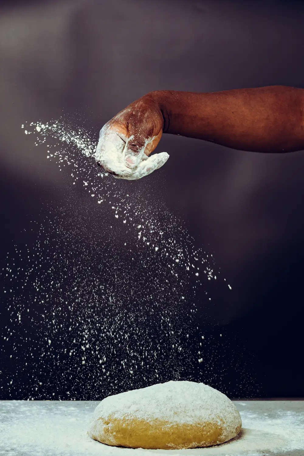 Person sprinkling flour for kneading dough
