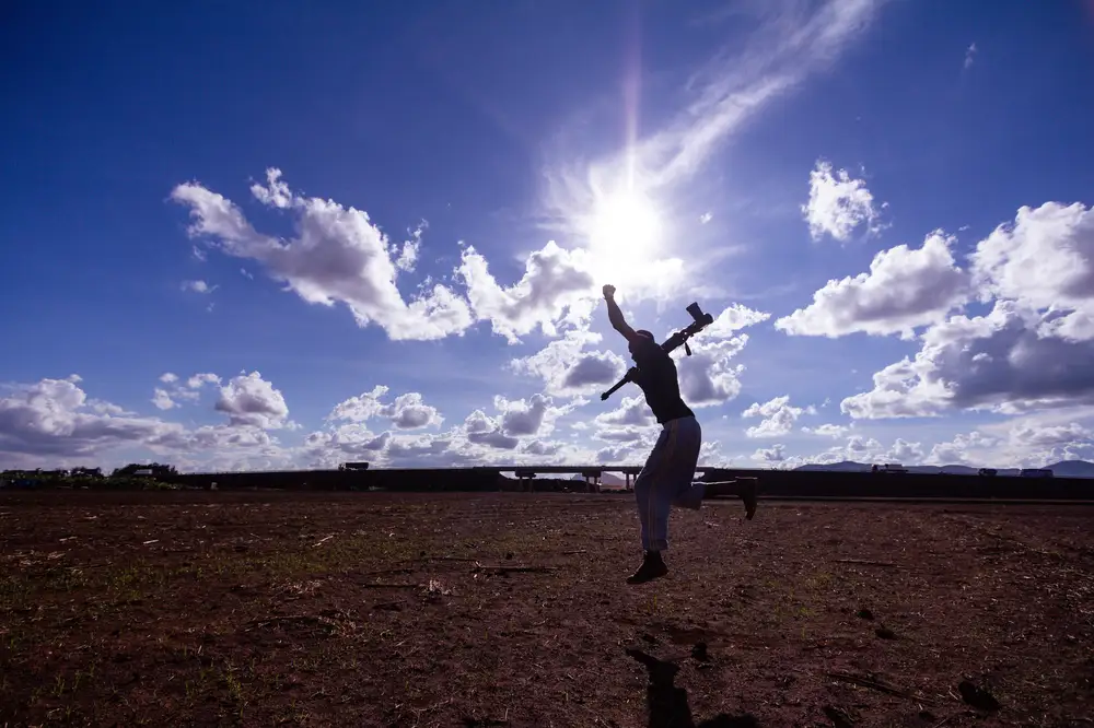 Man holding a shotgun and jumping in a desert