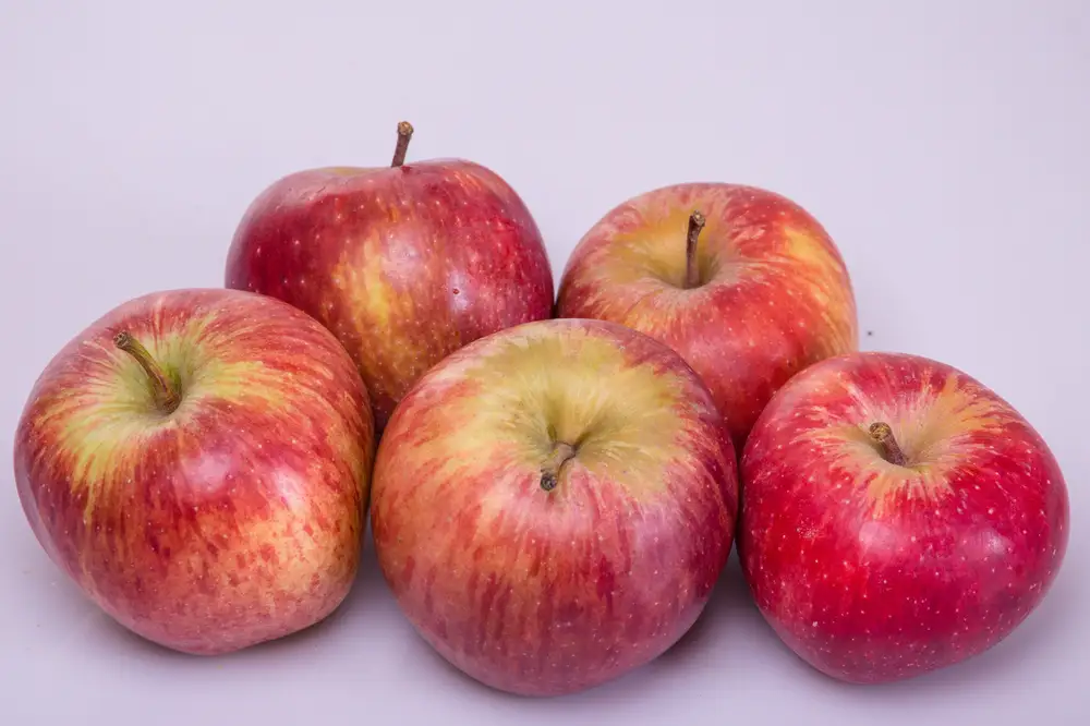 Five Big red apples on a plain surface