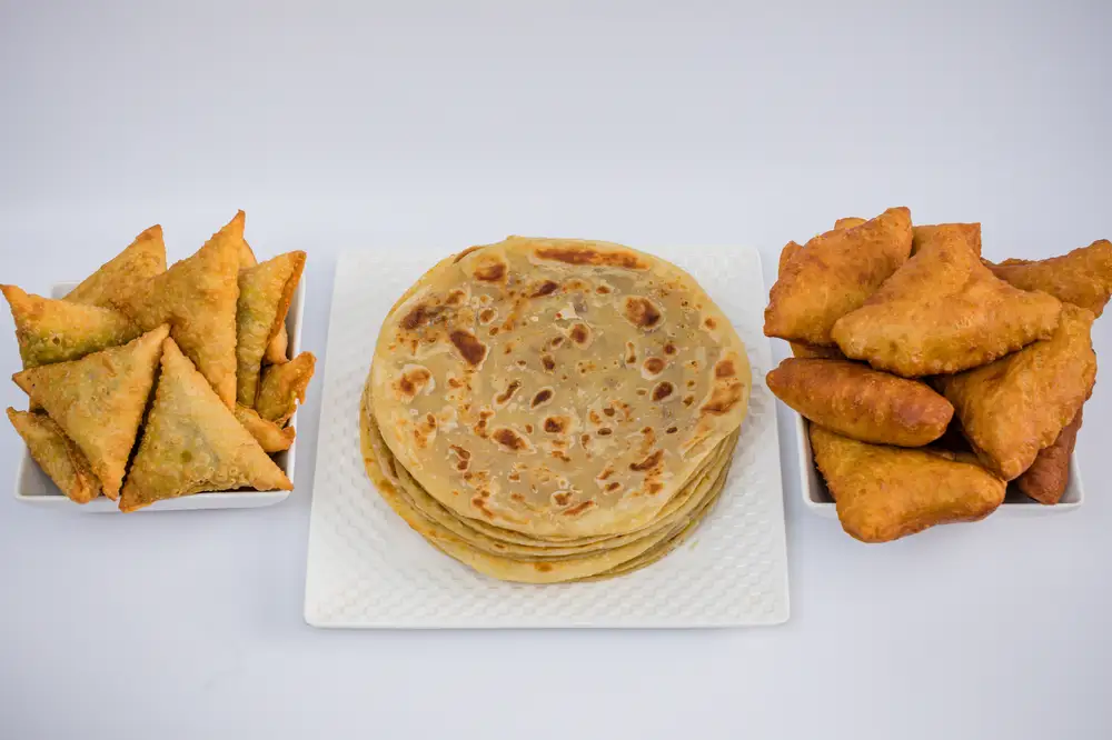 Bowls of samosa and sudanese bread with a plate of chapati